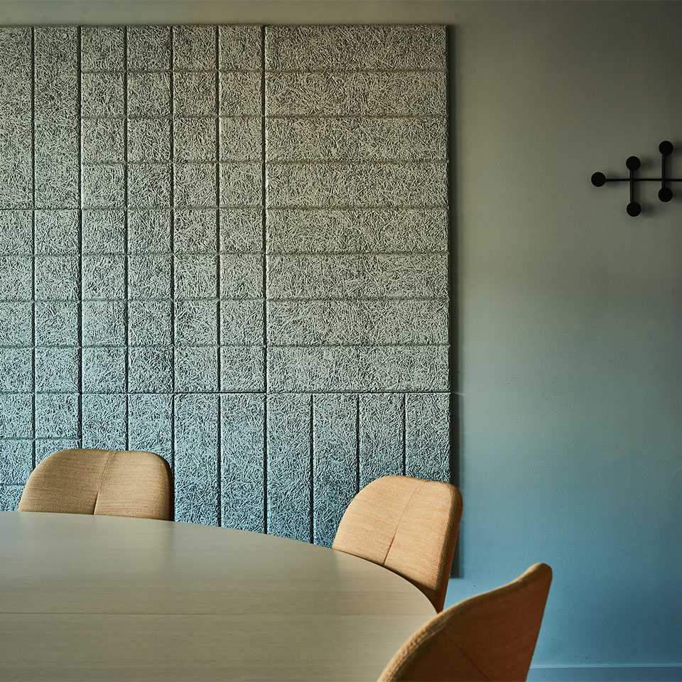 The conference room table and chairs in front of the acoustic panels